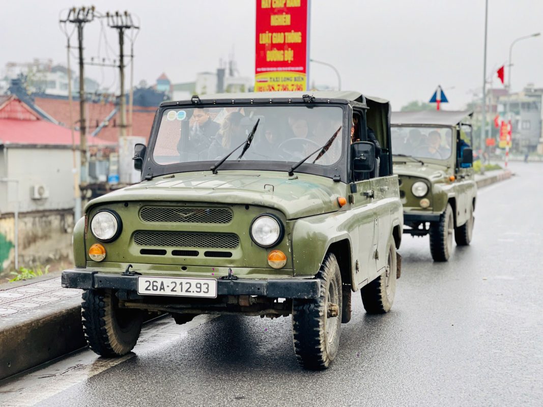Classic military Jeep carrying tourists along the iconic streets of Hanoi