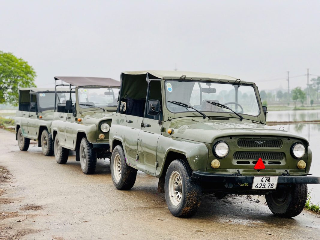 Tourists exploring the peaceful Hanoi countryside in a vintage army Jeep during a Hanoi Jeep Tour