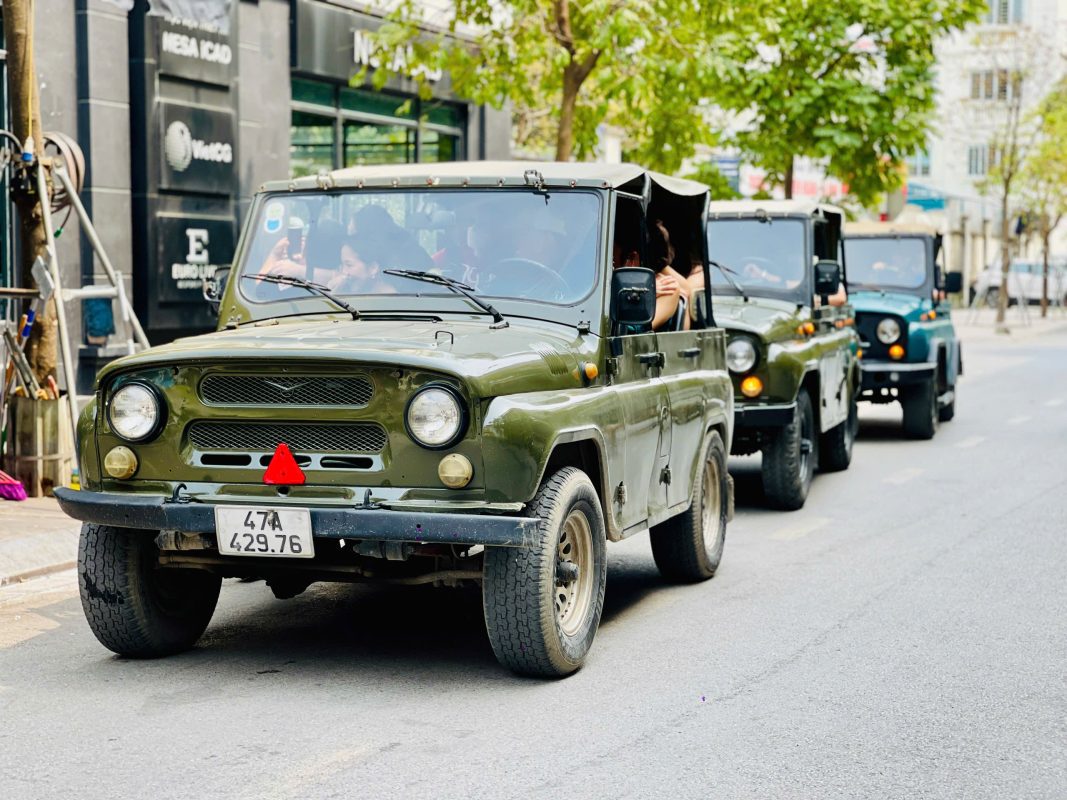 Tourists enjoying panoramic views from a moving Jeep in Hanoi